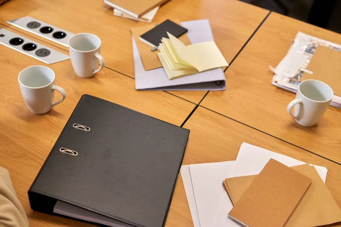 Binders and papers stacked on an office desk