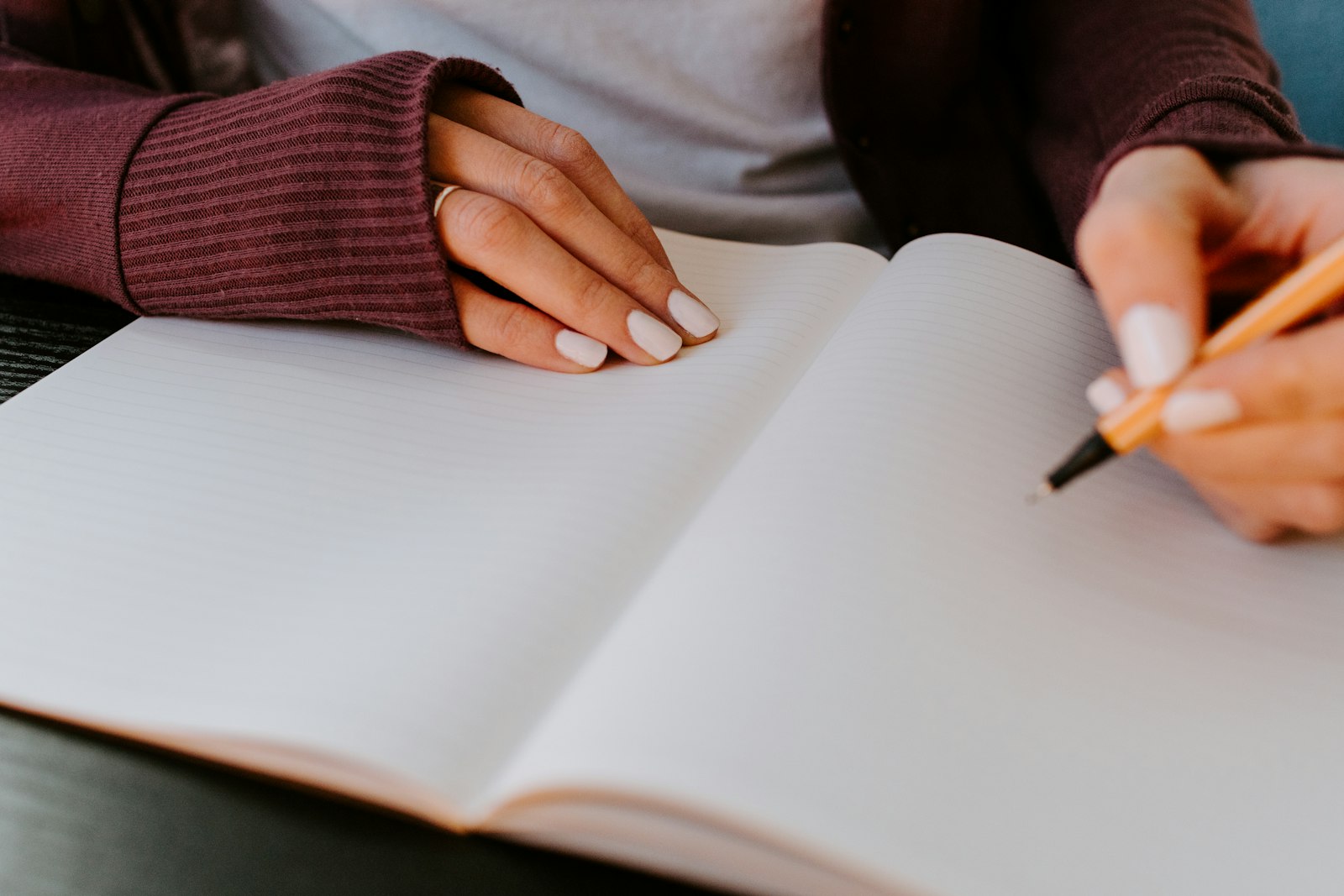 Hands writing in a notebook with a pen