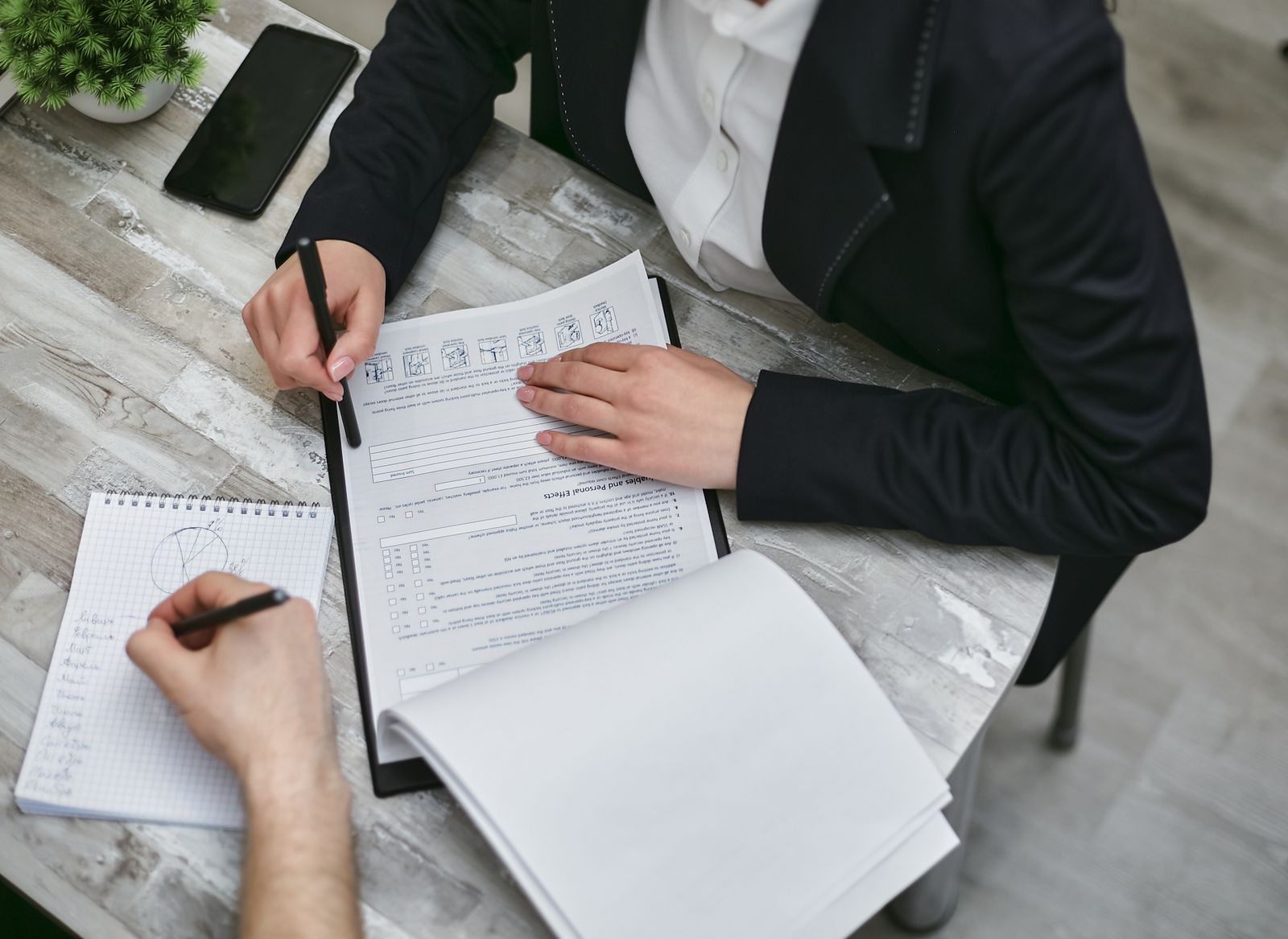 Two people at a desk marking up printed documents